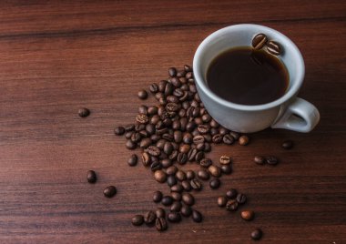 Fincan kahve kahve çekirdekleri ile bir ağaç üzerinde