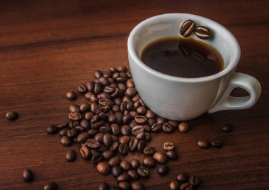 Fincan kahve kahve çekirdekleri ile bir ağaç üzerinde