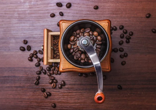 Кофейные зерна в кофемолке на дереве — стоковое фото
