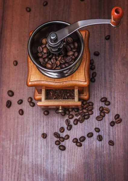 Кофейные зерна в кофемолке на дереве — стоковое фото