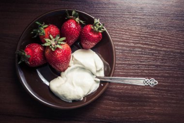 Çilek kremi bir plaka üzerinde bir kaşıkla