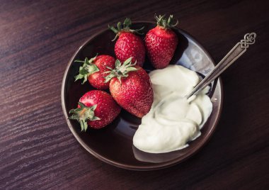 Çilek kremi bir plaka üzerinde bir kaşıkla