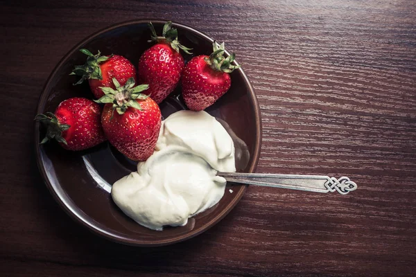 Fraises avec une cuillère de crème sur une assiette — Photo