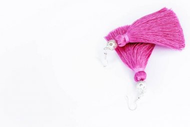 Beyaz bir arka plan üzerinde pembe el yapımı küpe.