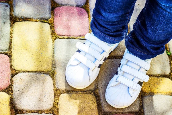 Benen av ett barn i vita sneakers och jeans — Stockfoto