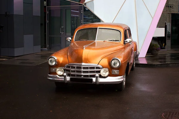 Antiguo coche naranja después de la lluvia sobre asfalto Fotos De Stock