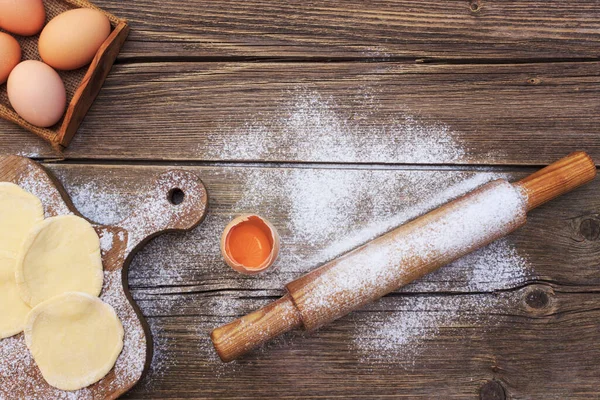 Baking cake in rural kitchen - dough recipe ingredients eggs, flour, milk, butter, sugar on vintage wooden table from above. Background layout with free text space.