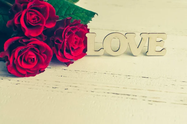 Röda rosor blommor med trä ordet kärlek — Stockfoto