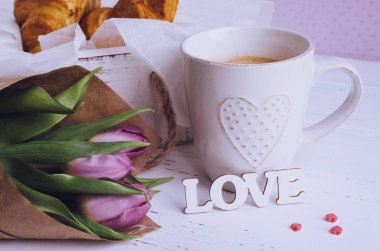 Kahve ay çöreği, buket pembe laleler ve ahşap kelime aşk ile