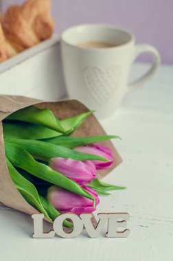 Kahve ay çöreği, buket pembe laleler ve ahşap kelime aşk ile