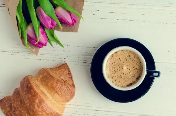 Xícara de café com buquê de tulipas rosa e croissant — Fotografia de Stock