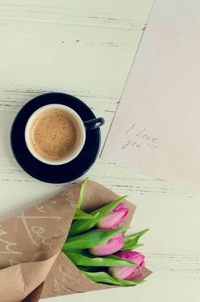 Xícara de café com buquê de tulipas rosa e notas Eu te amo — Fotografia de Stock