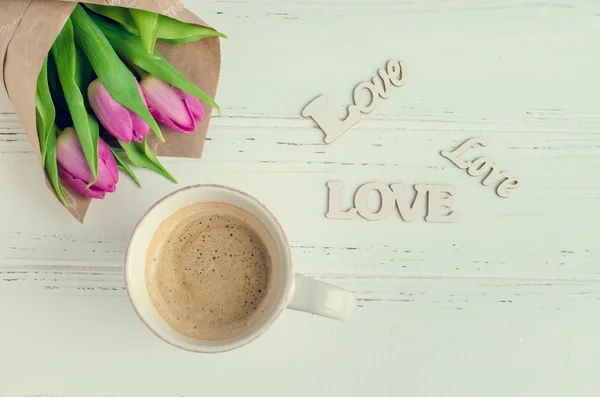 Taza de café con ramo de tulipanes rosados y palabras de madera AMOR —  Fotos de Stock