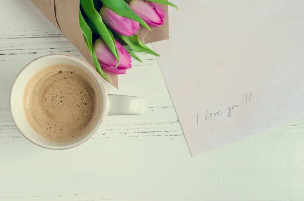 Xícara de café com buquê de tulipas rosa e notas Eu te amo — Fotografia de Stock