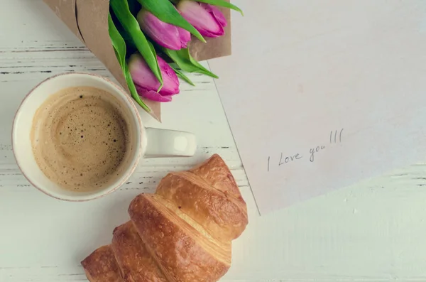 Taza de café con croissant, ramo de tulipanes rosados y notas I LOVE YOU —  Fotos de Stock