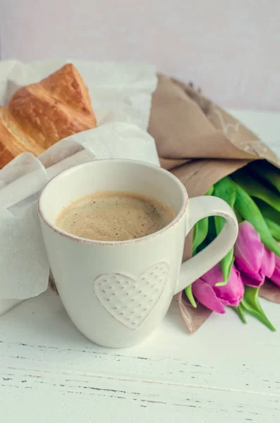 Kopp kaffe med bukett av rosa tulpaner och croissanter — Stockfoto