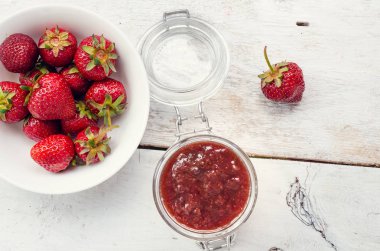 Ahşap arka planda bir kavanozda çilek reçeli