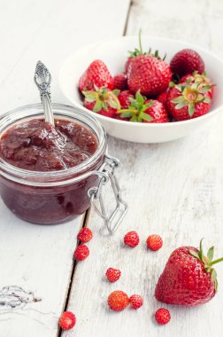 Ahşap arka planda bir kavanozda çilek reçeli