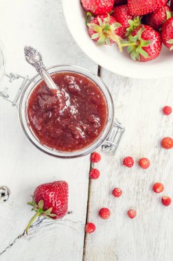 Ahşap arka planda bir kavanozda çilek reçeli