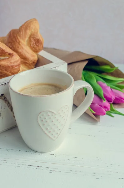 Kopp kaffe med bukett av rosa tulpaner och croissanter — Stockfoto