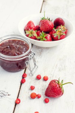 Ahşap arka planda bir kavanozda çilek reçeli