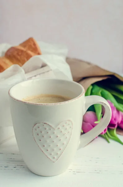 Kopp kaffe med bukett av rosa tulpaner och croissanter — Stockfoto