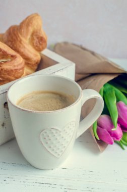 Fincan kahve kokulu pembe laleler ve kruvasan