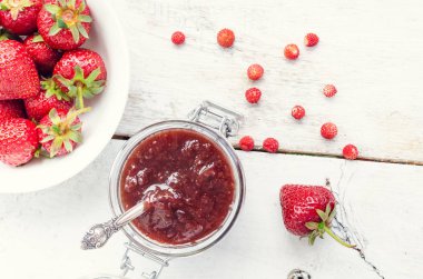 Ahşap arka planda bir kavanozda çilek reçeli