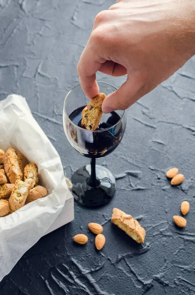 Trempage à la main de biscuits italiens cantuccini dans du vin rouge — Photo