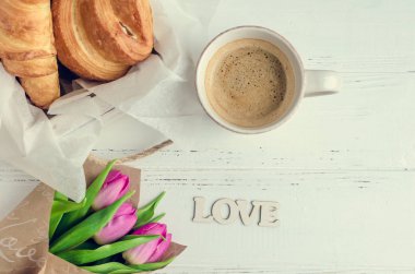 Ay çöreği, buket pembe laleler ve ahşap kelime aşk ile kahve fincan beyaz eski püskü şık arka planda. Romantik Sevgililer sabah kavramı. Sevgililer günü kahvaltı. Üstten Görünüm.