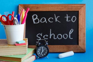 İleti örneği ile kavramı okul için geri. Okul üzerinde mavi arka plan sağlar. Tahtaya yazılmış okul frase tekrar. Çuval kitap, saat ve tebeşir ile fer'î çalışmalar.