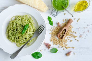 Beyaz ahşap masa üzerinde ev yapımı pesto soslu spagetti. Pesto alla Cenevizli ile makarna. İtalyan mutfağı kavramı. Üstten Görünüm.
