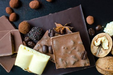 Farklı tür bir çikolata: karanlık, süt, şeker, fındık, tarçın ve anason siyah arka plan üzerinde gözenekli çubuklarıyla. Üstten Görünüm.