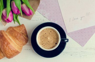 Kruvasan, buket pembe laleler ve beyaz eski püskü şık arka plan üzerinde aşk notları ile kahve fincan. Romantik Sevgililer sabah kavramı. Sevgililer günü kahvaltı. Üstten Görünüm.