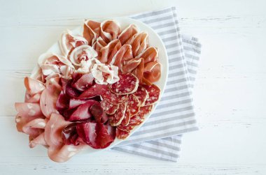 Soğuk et tabağı ile domuz eti, jambon, salam ve bresaola Beyaz ahşap zemin üzerinde füme. Şarap meze küme. İtalyan yemeği. Üstten Görünüm.