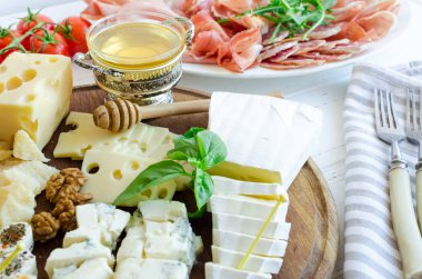 Peynir tabağı: Brie, Parmesan, kaşar peyniri, gouda, gorgonzola ve diğer ceviz ve ballı ahşap tahta üzerinde. Lezzetli meze peynir farklı tipteki. Parti ya da piknik zamanında lezzetli aperatif.