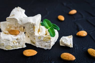 Tatlı nuga siyah taş zemin üzerine badem ile. Beyaz nuga parçaları.