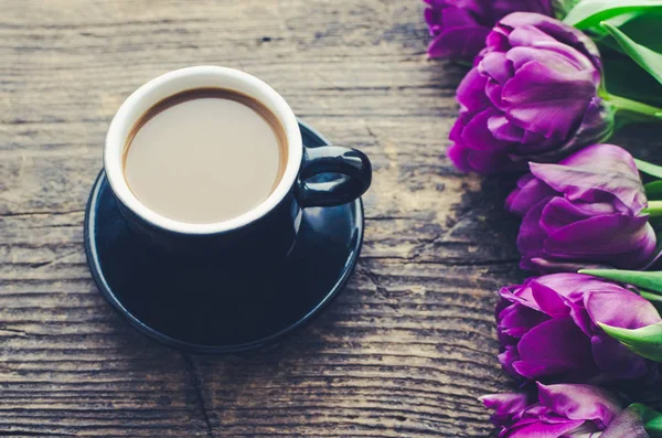 Xícara de café com buquê de tulipas roxas — Fotografia de Stock