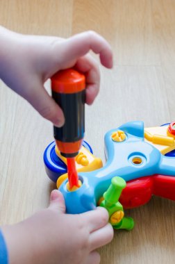Çocuk bir motosiklet ile oynuyor. Bebek parmaklar oyuncak bir tornavida yardımı ile toplamak. Renkli Ayrıntılar çocuk dikkat çekmek. Oyun kapalı yerde gerçekleşir.