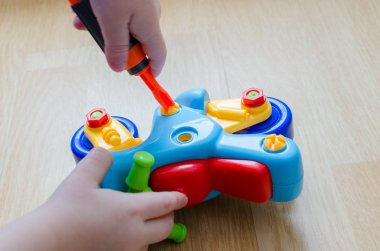 Çocuk bir motosiklet ile oynuyor. Bebek parmaklar oyuncak bir tornavida yardımı ile toplamak. Renkli Ayrıntılar çocuk dikkat çekmek. Oyun kapalı yerde gerçekleşir.