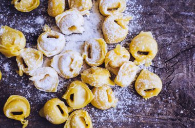 Taze ev yapımı ham flouring tortellini ahşap vintage kesme tahtası üzerinde pişirmek hazır hazır. Geleneksel İtalyan mutfağı kavramı. Üstten Görünüm.