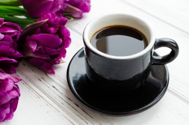 Kahve ve çiçek Lale. Bir fincan kahve ve mor laleler beyaz tahta masada. Kahvaltı anneler günü, Sevgililer günü veya kadın gün. Bahar arka plan.