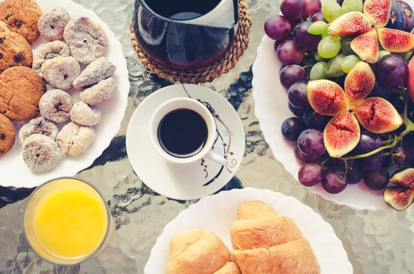 Mesa de desayuno con café, zumo de naranja, frutas y croissants — Foto de Stock