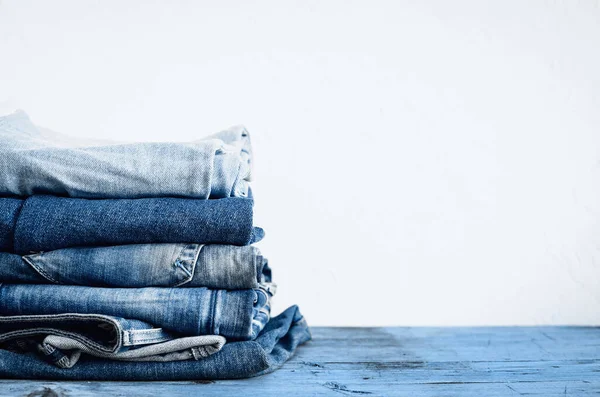 Jeans empilhados em uma mesa de madeira — Fotografia de Stock