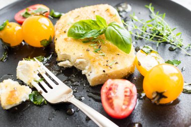 Ekmek kırıntılarıyla kaplanmış tavada tuzlu peynir, biberli kekik balı ve renkli domatesli kirazlı. Vejetaryen sağlıklı gıda konsepti.