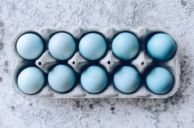 Boyanmış mavi Paskalya yumurtaları, gri beton arka planda doğal boya kırmızısı lahanayla boyanmış. Bir sıra mavi ombre paskalya yumurtası. Gıda boyasıyla doğal ekolojik lekeler. Üst görünüm.