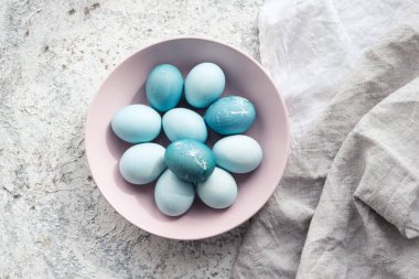 Mavi Paskalya yumurtaları, gri beton arka planda doğal boya kırmızısı lahanayla boyanmış. Bir sıra mavi ombre paskalya yumurtası. Gıda boyasıyla doğal ekolojik lekeler. Üst görünüm.