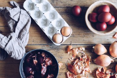 Kırsal ahşap arka planda doğal boya soğanıyla boyanmış Paskalya yumurtaları. Paskalya için doğal boya ile yumurta boyama işlemi. Gıda boyasıyla doğal ekolojik lekeler. Üst görünüm.