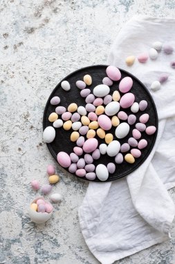 Paskalya kompozisyonu, gri beton arka planda pastel renkli mini çikolatalı yumurtalar. Mutlu Paskalyalar. Üst Manzara. Boşluğu kopyala.