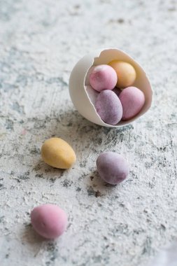 Paskalya kompozisyonu, gri beton arka planda pastel renkli mini çikolatalı yumurtalar. Mutlu Paskalyalar. Boşluğu kopyala.
